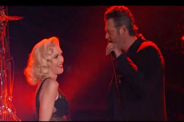 A man and woman sing passionately on stage under red lighting. A man and woman sing passionately on stage under red lighting.