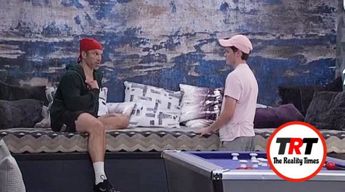 Two men sitting and talking near a pool table against a textured wall. Two men sitting and talking near a pool table against a textured wall.