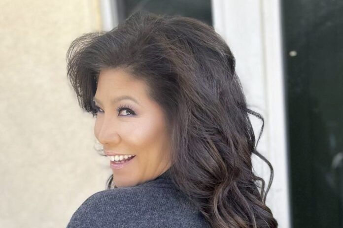 A woman with dark, voluminous hair smiling over her shoulder. A woman with dark, voluminous hair smiling over her shoulder.