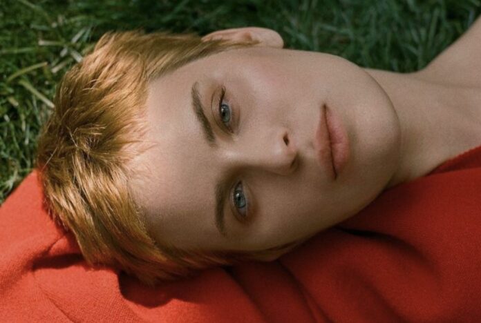 Close-up of a person with short hair lying on grass, wearing a red shirt. Close-up of a person with short hair lying on grass, wearing a red shirt.