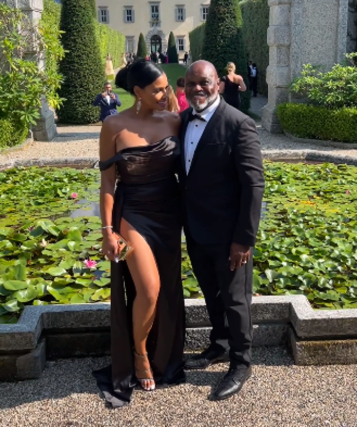 A couple dressed elegantly, smiling outdoors by a pond with lily pads. A couple dressed elegantly, smiling outdoors by a pond with lily pads.