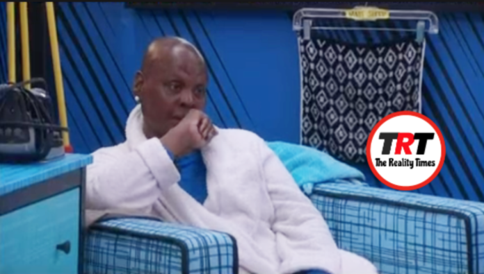 Man in white robe sitting pensively on blue checkered couch. Man in white robe sitting pensively on blue checkered couch.