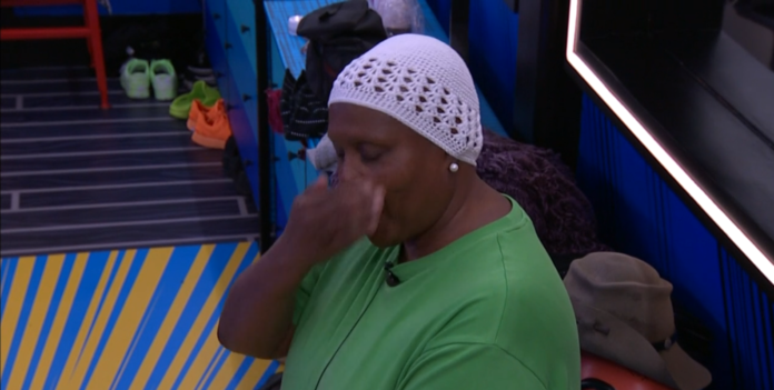 Person in a green shirt and white crocheted hat touching their nose. Person in a green shirt and white crocheted hat touching their nose.