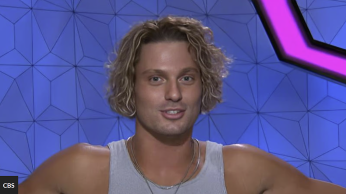 Young man with curly blonde hair in a gray tank top against a geometric blue background. Young man with curly blonde hair in a gray tank top against a geometric blue background.