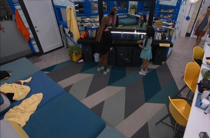 Two women standing near a counter in a modern indoor space with patterned flooring. Two women standing near a counter in a modern indoor space with patterned flooring.
