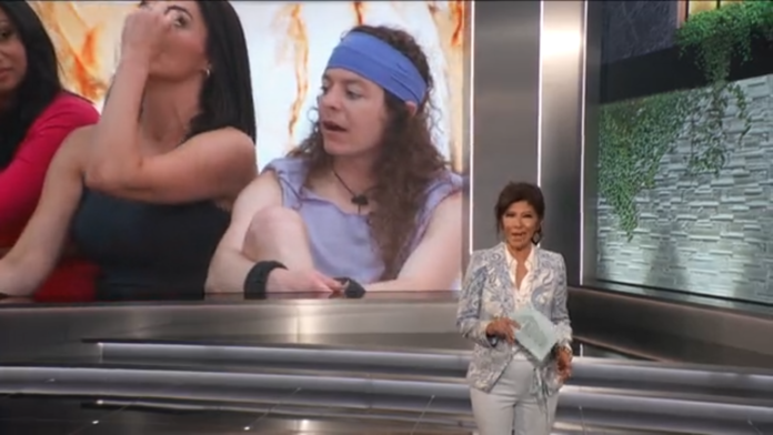 A woman presenting in front of a large screen showing a young person in a blue headband. A woman presenting in front of a large screen showing a young person in a blue headband.