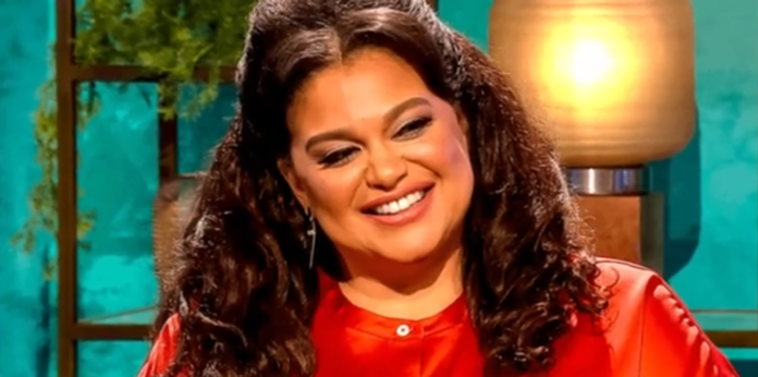 A woman with curly hair smiling warmly during an interview. A woman with curly hair smiling warmly during an interview.