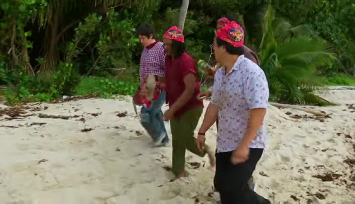 Four men walking on sandy ground in a lush green outdoor setting. Four men walking on sandy ground in a lush green outdoor setting.