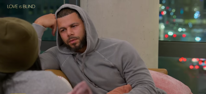 Man in gray hoodie leaning back with a thoughtful expression. Man in gray hoodie leaning back with a thoughtful expression.