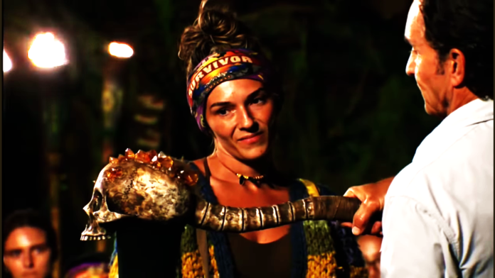 A contestant holding a large mace in a tribal setting. A contestant holding a large mace in a tribal setting.