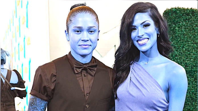 Two women smiling, one in a black suit and bow tie, the other in a blue dress. Two women smiling, one in a black suit and bow tie, the other in a blue dress.