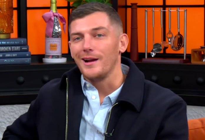 A man speaking in a studio with orange background and fire extinguisher. A man speaking in a studio with orange background and fire extinguisher.