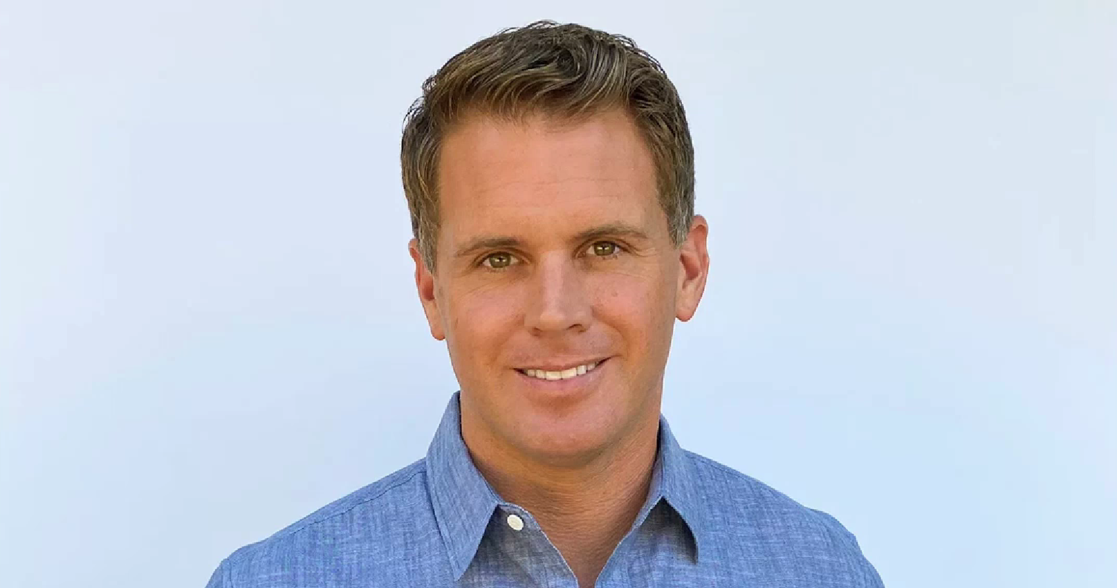Smiling man in a blue shirt with a light background. Smiling man in a blue shirt with a light background.
