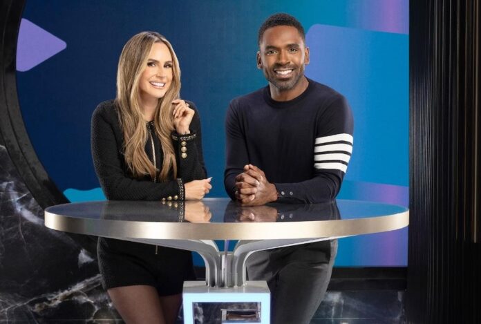 Two hosts sitting at a round table, smiling at the camera. Two hosts sitting at a round table, smiling at the camera.