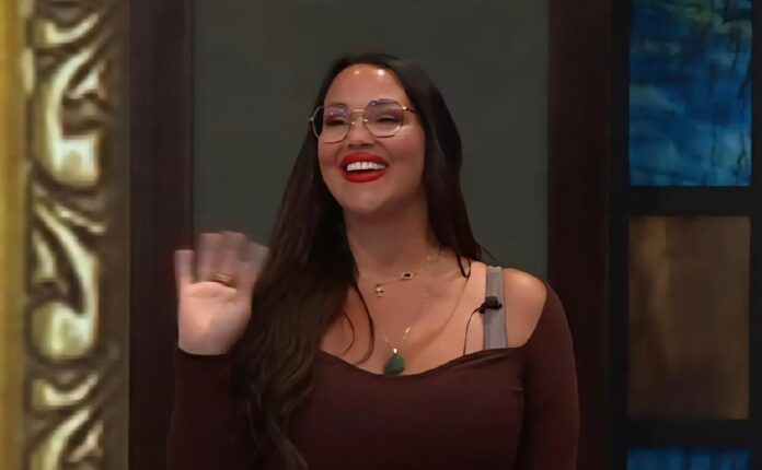 A smiling woman with long hair and glasses waves cheerfully. A smiling woman with long hair and glasses waves cheerfully.