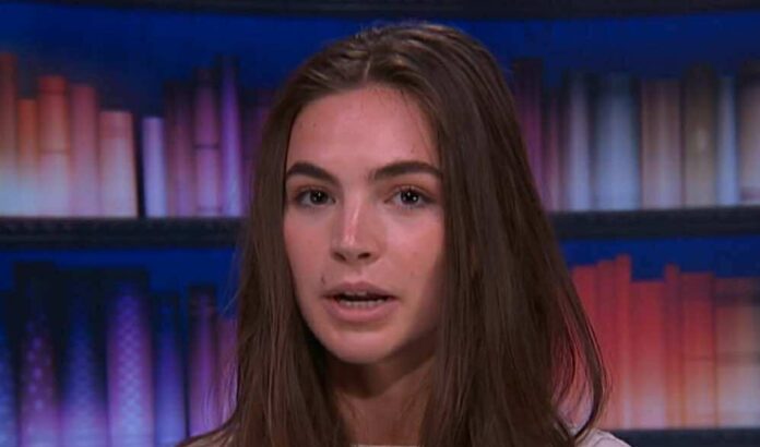 Young woman speaking in a studio with bookshelves behind her. Young woman speaking in a studio with bookshelves behind her.