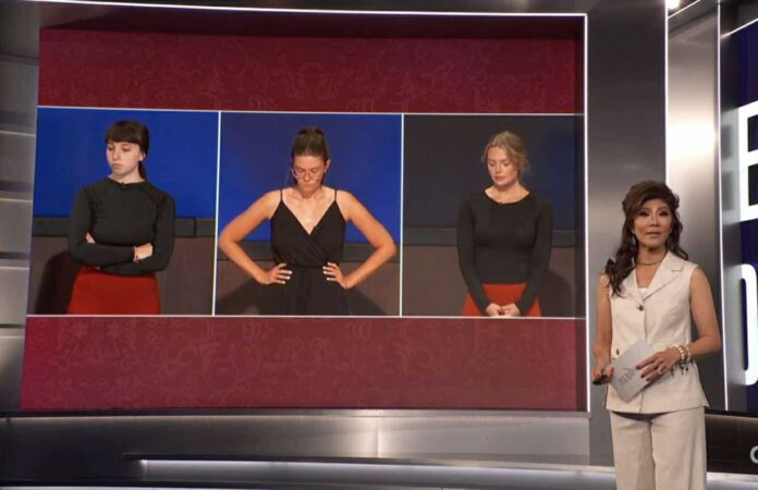 Three women standing with arms crossed on a stage in a competition setting. Three women standing with arms crossed on a stage in a competition setting.