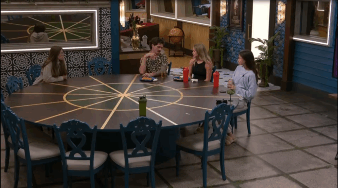 Four people sitting and talking around a large outdoor table at night. Four people sitting and talking around a large outdoor table at night.