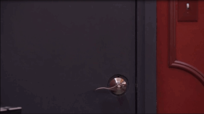 Hand turns a door handle to open a dark door. Hand turns a door handle to open a dark door.