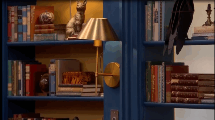 A cozy bookshelf with a cat statue, lamp, and books. A cozy bookshelf with a cat statue, lamp, and books.