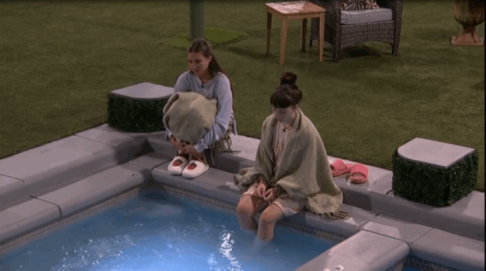 Two women sitting by a pool, dipping their feet in the water at night. Two women sitting by a pool, dipping their feet in the water at night.