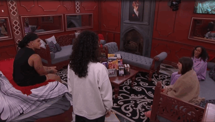 Person standing in a red-themed cozy room with couches and fireplace. Person standing in a red-themed cozy room with couches and fireplace.