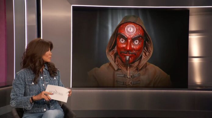A news anchor interviews a guest with a digitally altered face resembling a red demon. A news anchor interviews a guest with a digitally altered face resembling a red demon.