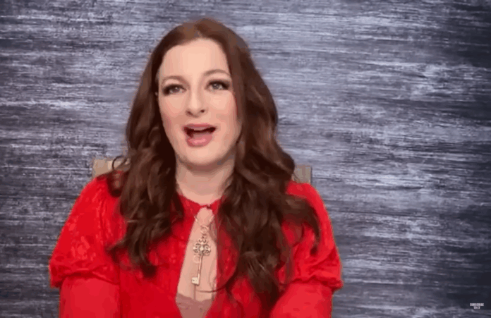 Woman in red blouse speaking with enthusiasm against a gray backdrop. Woman in red blouse speaking with enthusiasm against a gray backdrop.