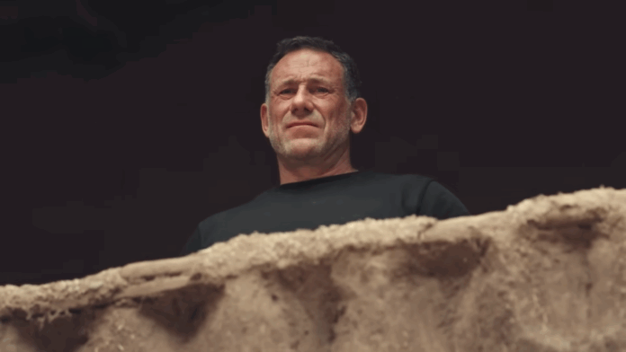 Man in black shirt looking down over a rough stone ledge. Man in black shirt looking down over a rough stone ledge.