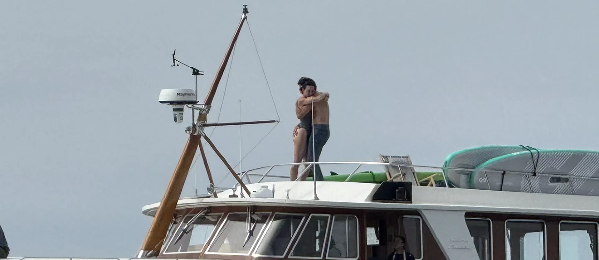 Couple embracing on a boat deck under a clear sky.