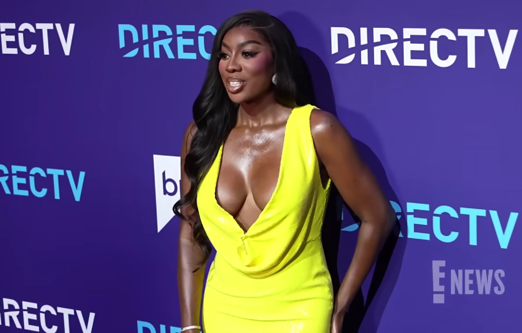 A woman in a vibrant yellow dress posing confidently at an event.